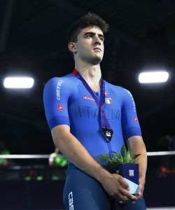 Matteo Bianchi in completo da bici blu dell'italia con in maso un vaso con all'interno una pianta