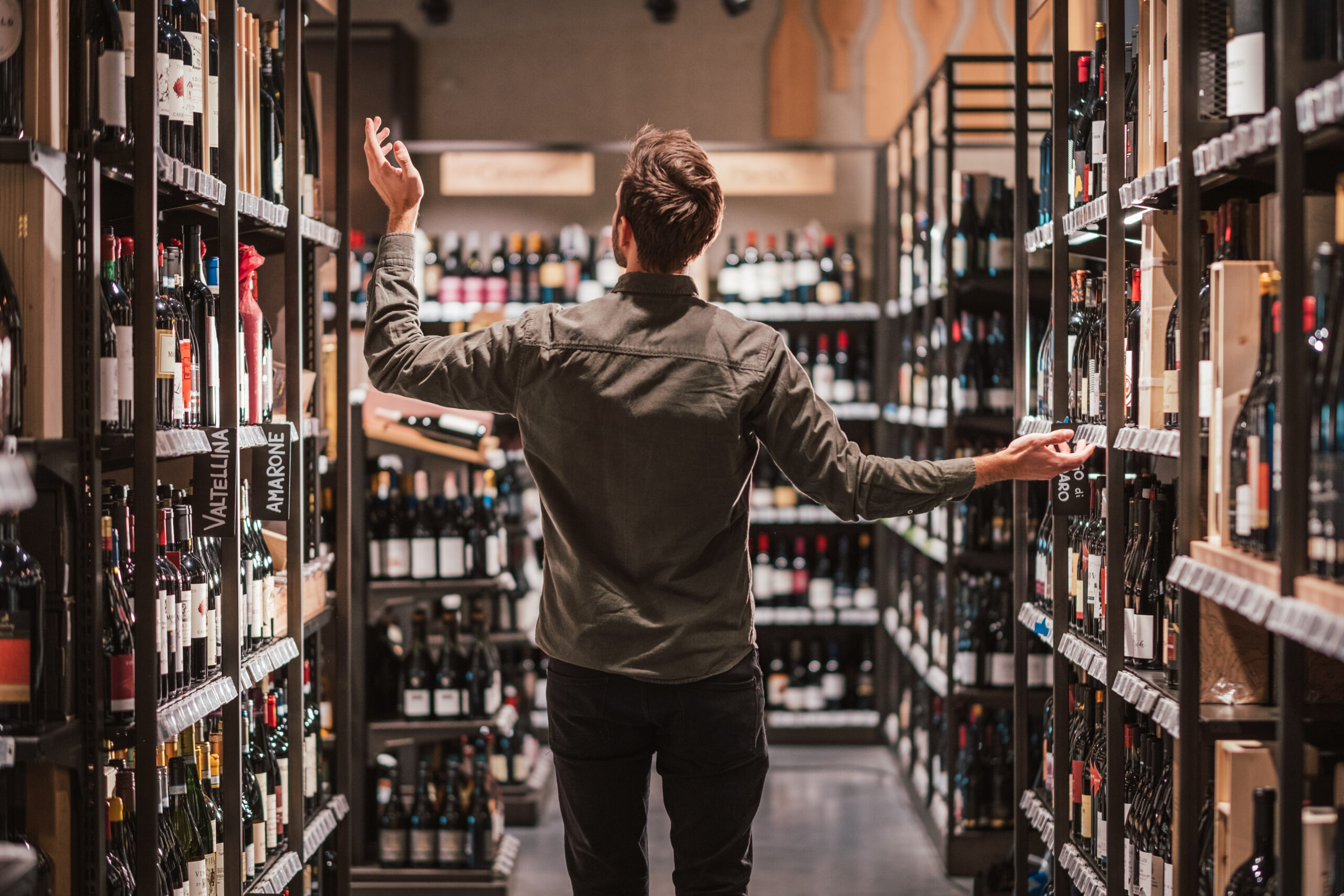 Uomo in mezzo ad una grande selezione di vini